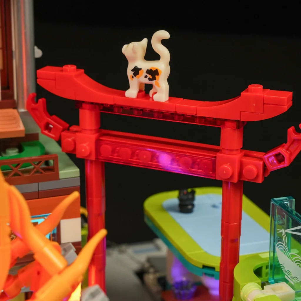 Kleine Katze auf einem roten japanischen Tor im Lumibricks Izakaya